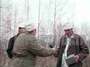 Men in white caps with a dosimeter in a birch forest, archival frame from Mayak plutonium plant and Soviet atomic bomb coverage.