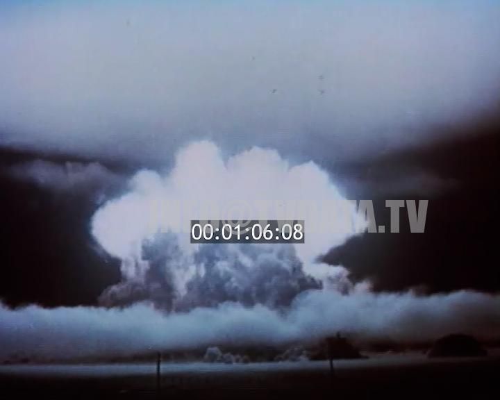 Wide-shot view of a massive nuclear explosion, capturing the towering mushroom cloud of smoke and fire, with an initial lens flare effect