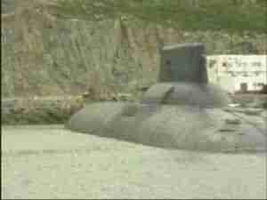 Submarine moored below rocky hills at a Northern Fleet base, archival frame from Kursk submarine coverage.