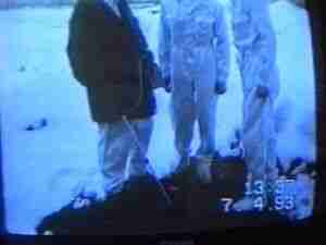 Television frame of men standing in snow at night, archival frame from Chernobyl nuclear accident coverage.