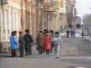 Pedestrians on a city street with old facades, archival frame from Chernobyl nuclear accident coverage.